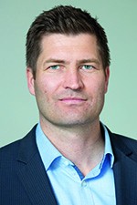 Ein Mann mittleren Alters mit einem hellblauen Hemd und dunkelblauen Jacket